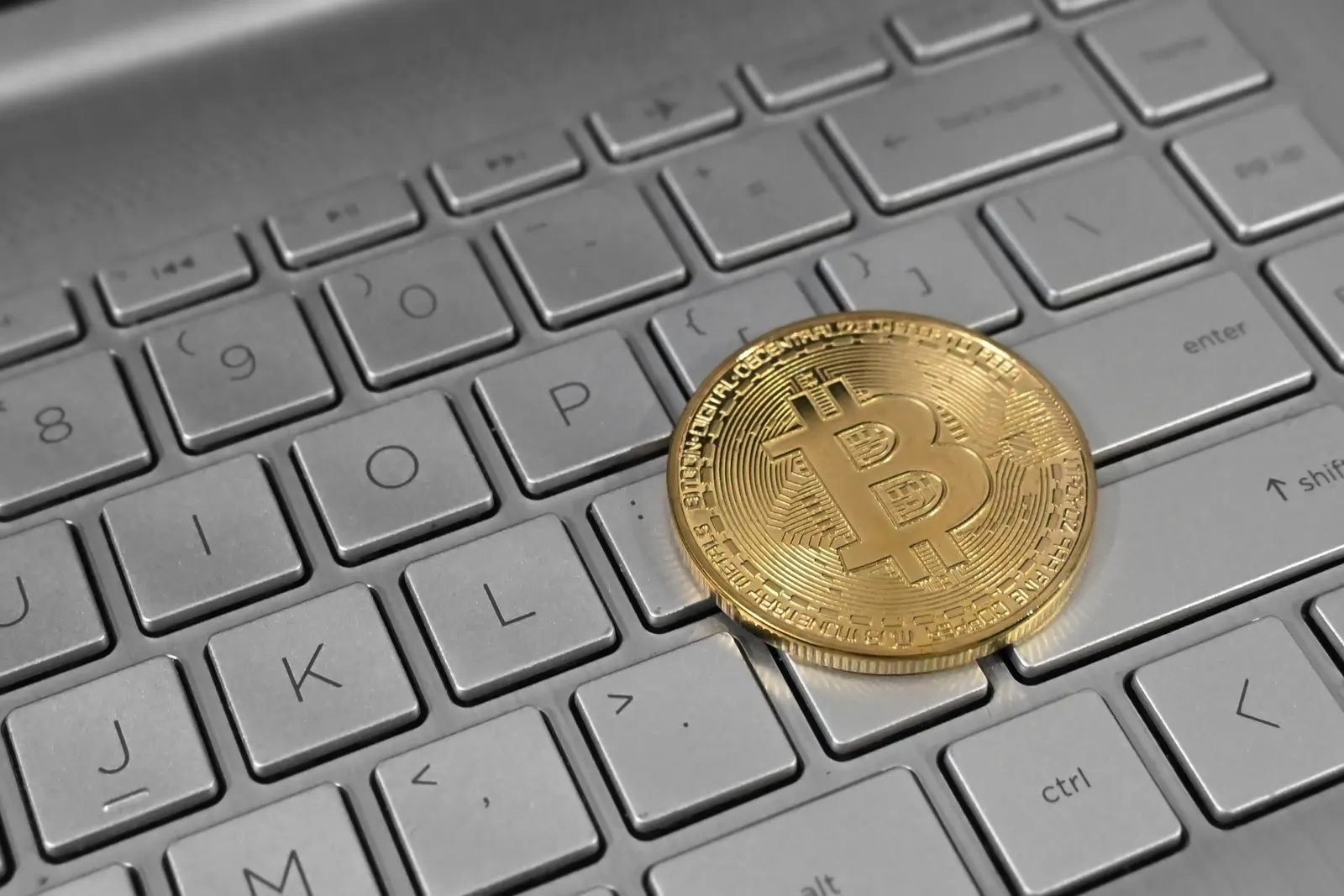 Una moneda de bitcoin sobre el teclado de una laptop